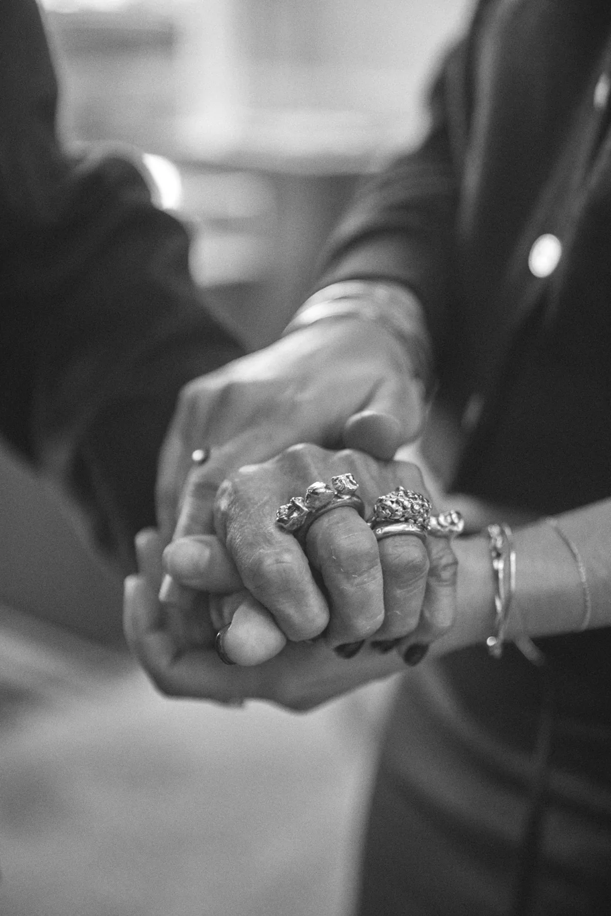 Two hands clasped, an older hand held inside a younger one