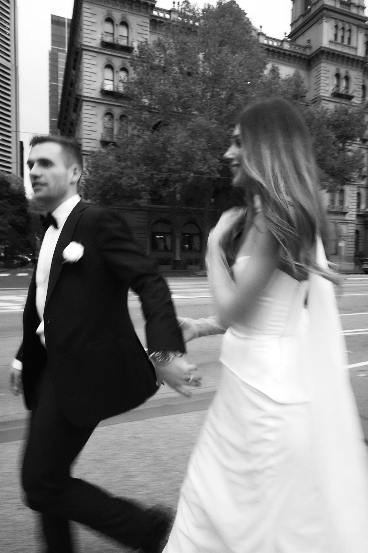Bride and groom crossing a Melbourne city street — black and white