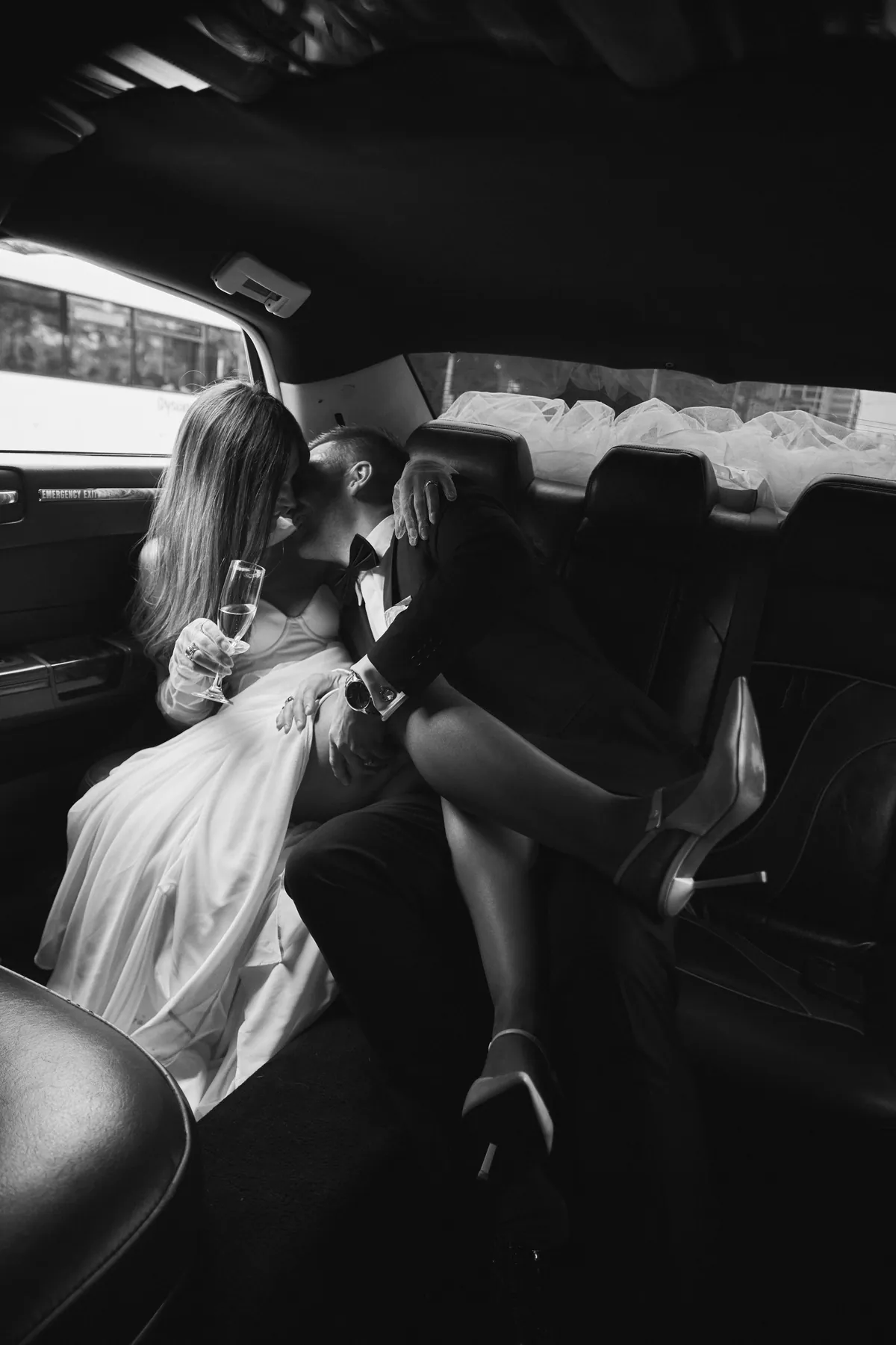 Newlyweds kissing in the back of the wedding car
