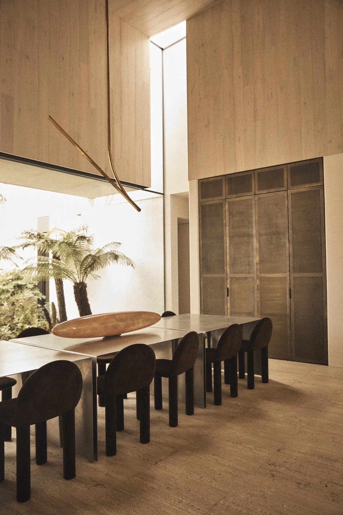 Warm timber-panelled dining room with a long table in afternoon light