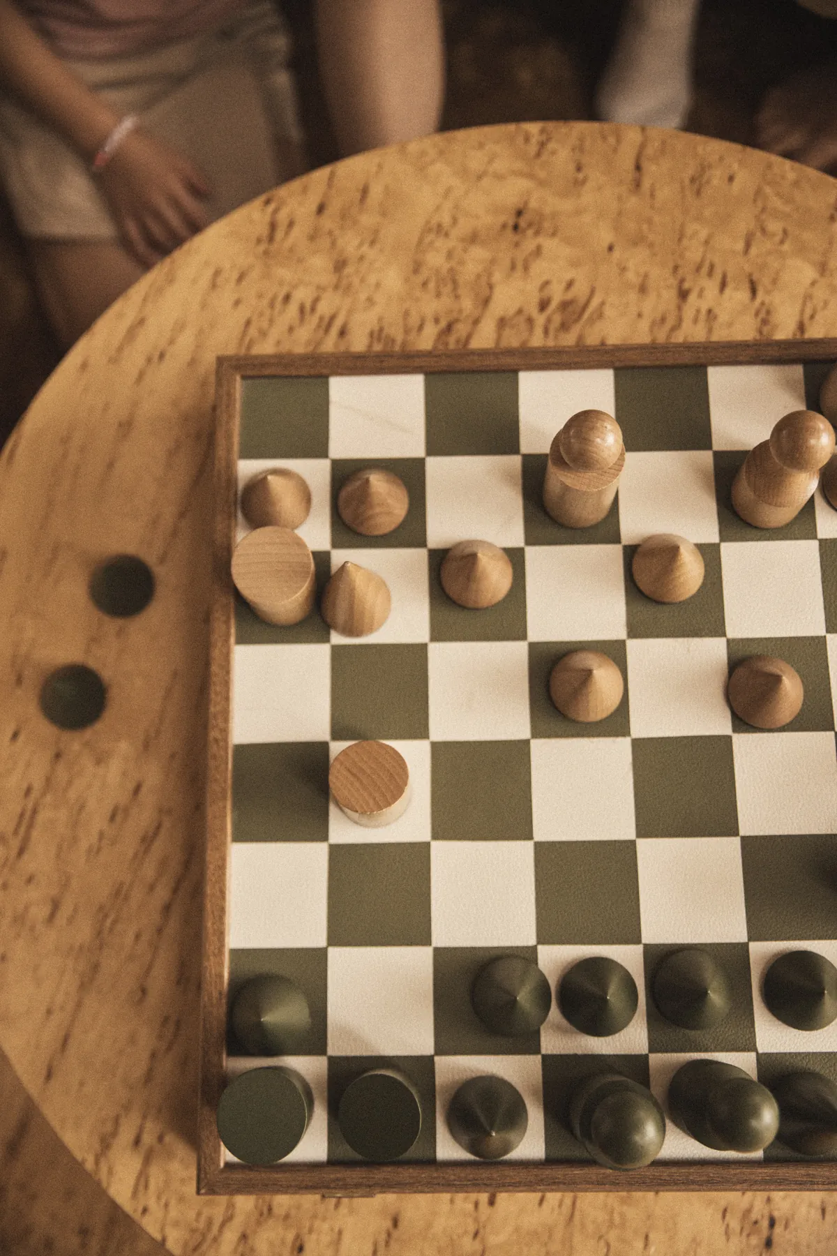 A chess game mid-play on a round timber table