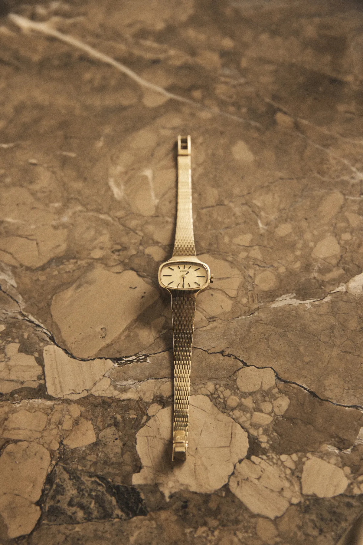 A vintage gold wristwatch resting on stone