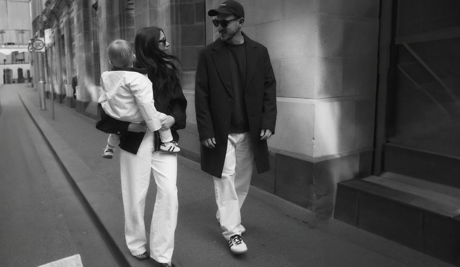 A mother carrying her toddler along a Melbourne laneway, the father walking beside them, photographed in black and white
