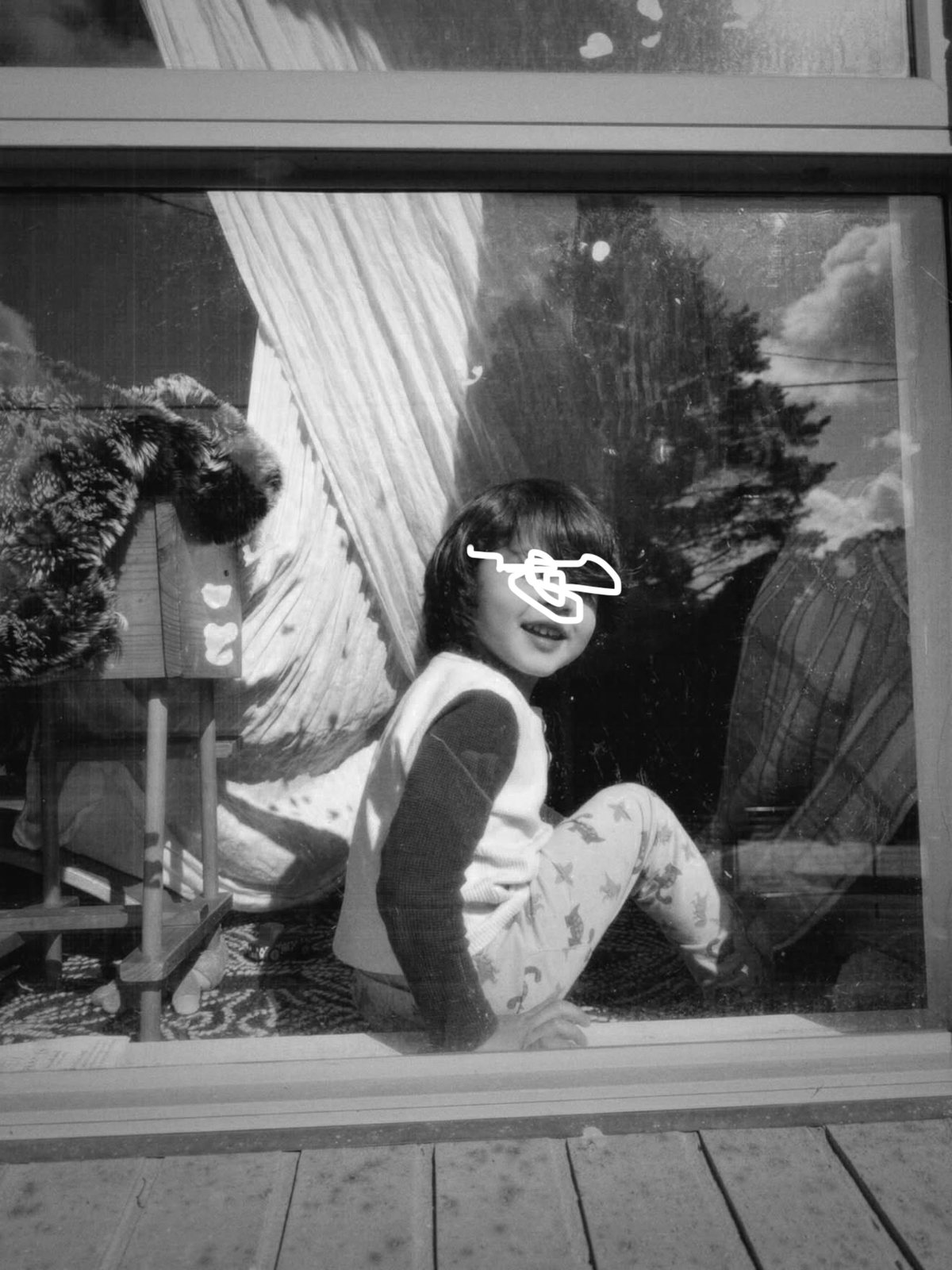 A child sitting in a sunlit window, photographed from outside through the glass by her mother — a reader of the guide